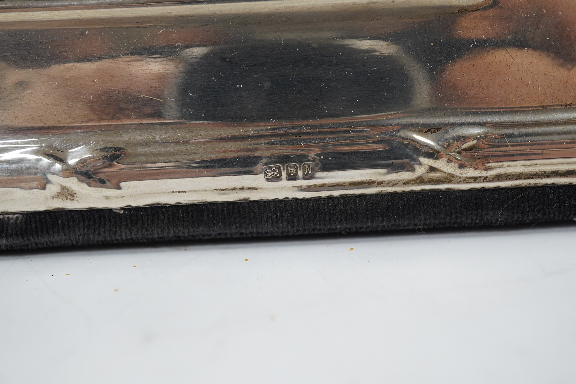 A George V silver two handled presentation trophy cup, 21.8cm, a modern silver wine coaster, a modern mounted silver photograph frame and a George V silver mounted photograph frame. Condition - poor to fair